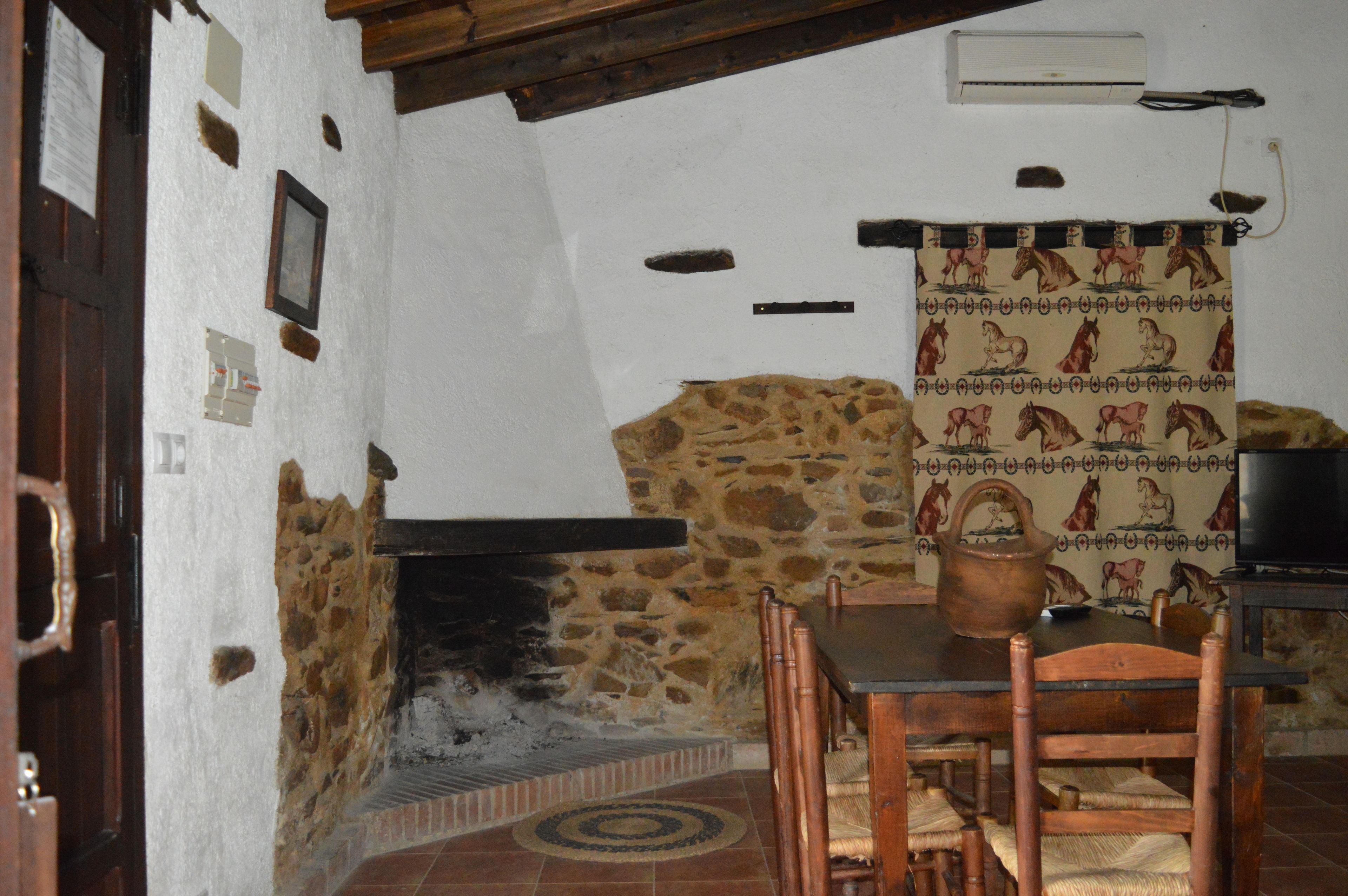A rustic room with a stone wall, a fireplace, wooden furniture, and a television.