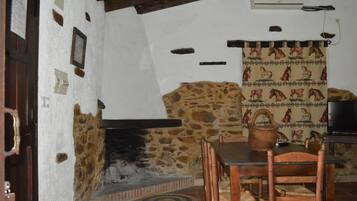 A rustic room with a stone wall, a fireplace, wooden furniture, and a television.