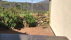 A patio with a wooden table and a stone wall. - One bedroom holiday home near the Snowdonia National Park (Caernarfon)