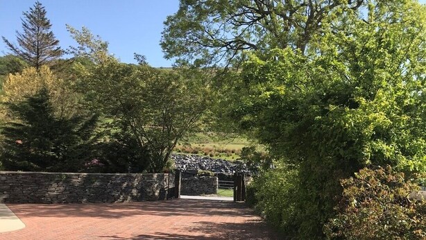 A paved pathway leading to a stone archway surrounded by lush greenery. - One bedroom holiday home near the Snowdonia National Park (Caernarfon)