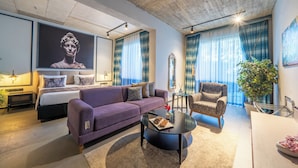 Una sala de estar moderna con un sofá, un sillón, una mesa de centro y una cama con cabecera.