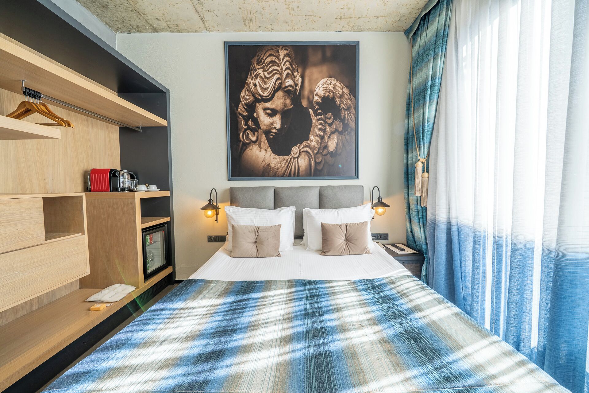 A bedroom with a bed, bedside lamps, a wardrobe, and a large framed artwork on the wall.
