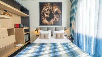 A bedroom with a bed, bedside lamps, a wardrobe, and a large framed artwork on the wall.