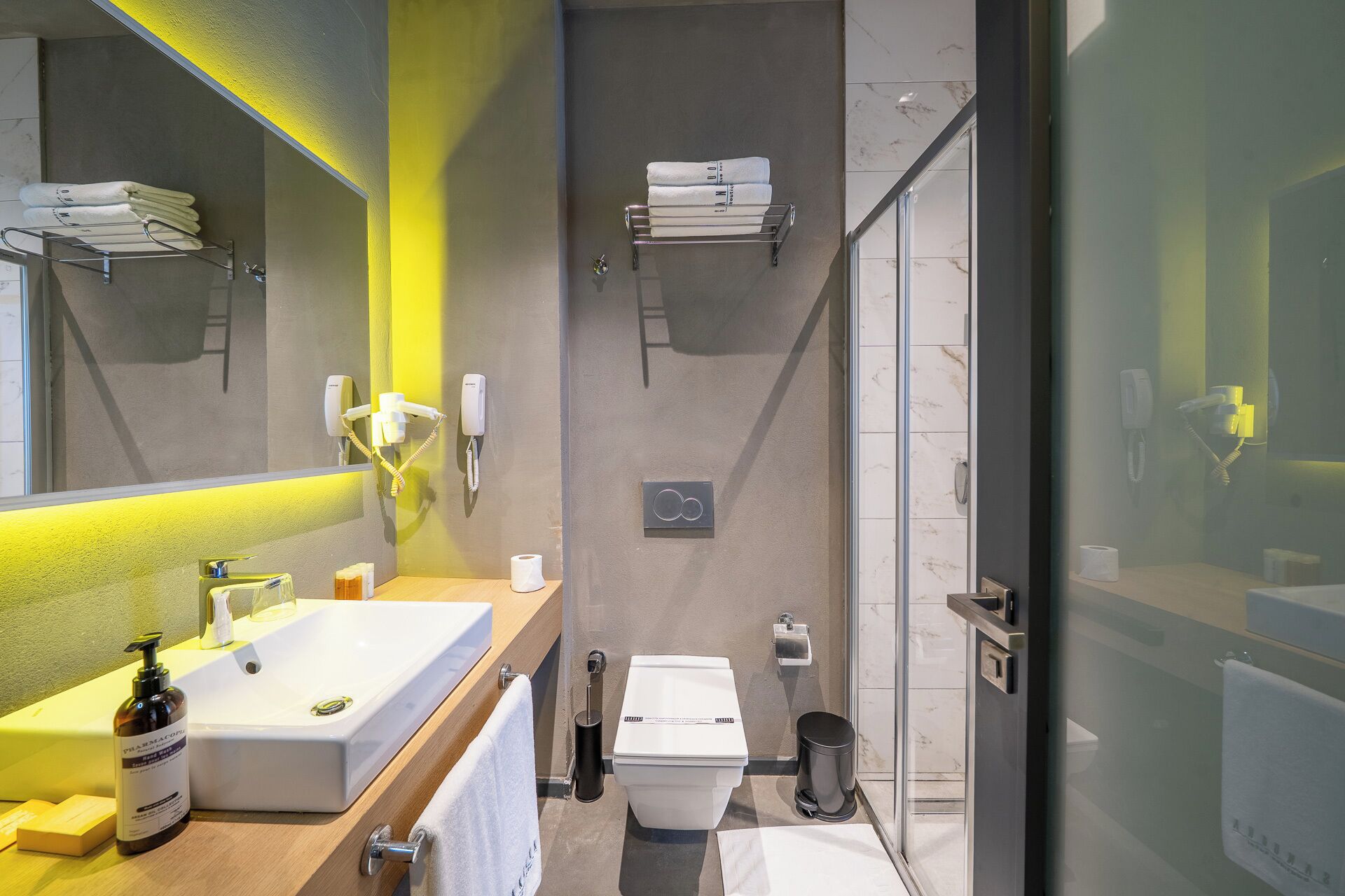 A modern bathroom with a large mirror, a sink, a toilet, and a shower area.