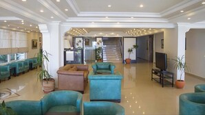 A spacious lobby with a reception desk, seating area, and a staircase leading to upper floors. - Amphora Hotel (Ayvalik)