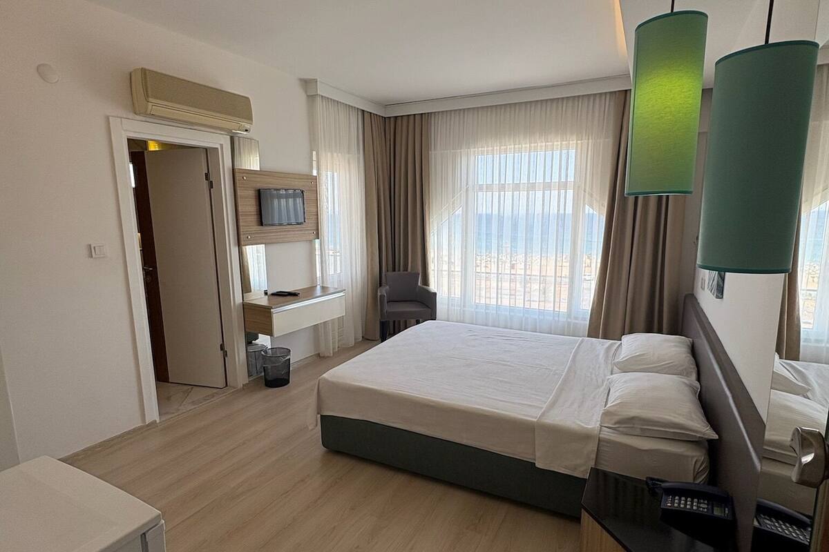 Ein Hotelzimmer mit einem Bett, einem Schreibtisch, einem Sessel und einem Fernseher.