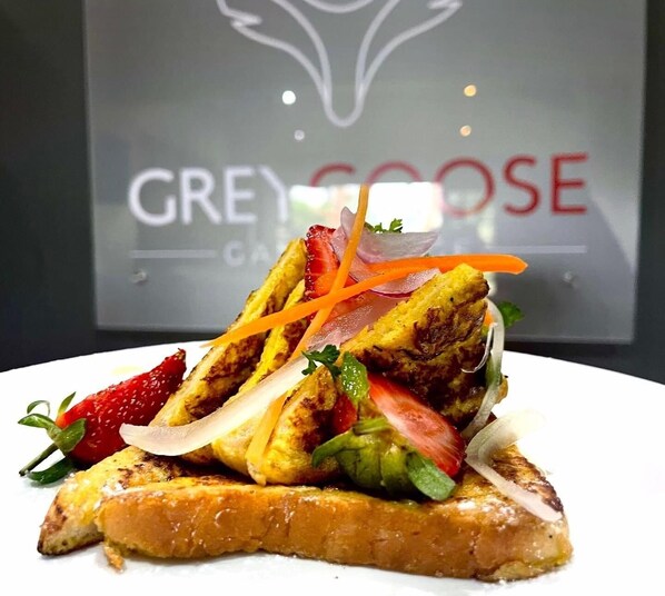 A sandwich with grilled chicken, vegetables, and a slice of bread on a white plate.