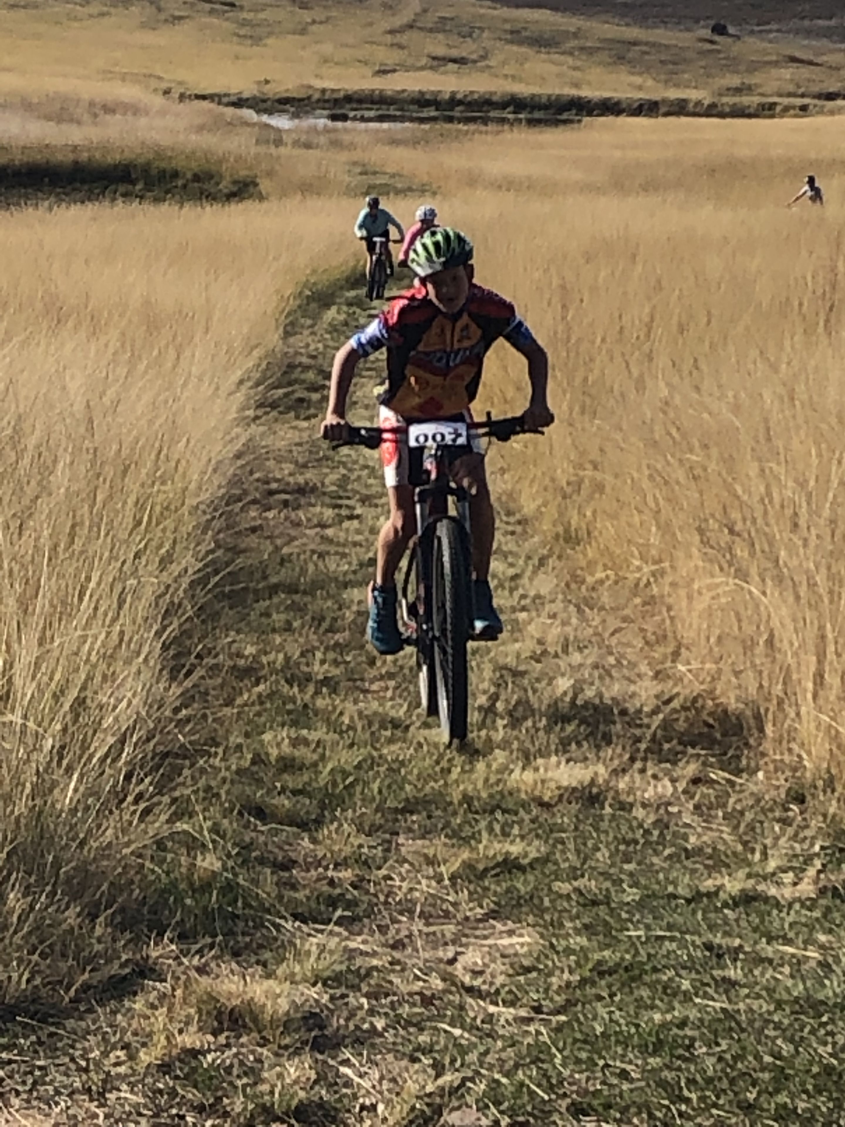 A cyclist in a field with a number tag, indicating a race or event.