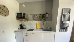 Una cocina compacta con microondas, fregadero y armarios de almacenamiento.