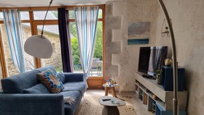 Una sala de estar con un sofá, una mesa de centro, televisor y una pequeña mesita de noche con juguetes.