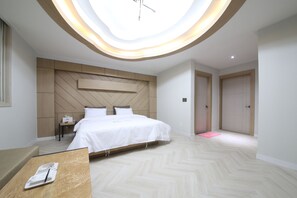 A modern hotel room with a large bed, a desk, a wooden headboard, and a skylight. - Eco Hotel (Mokpo)