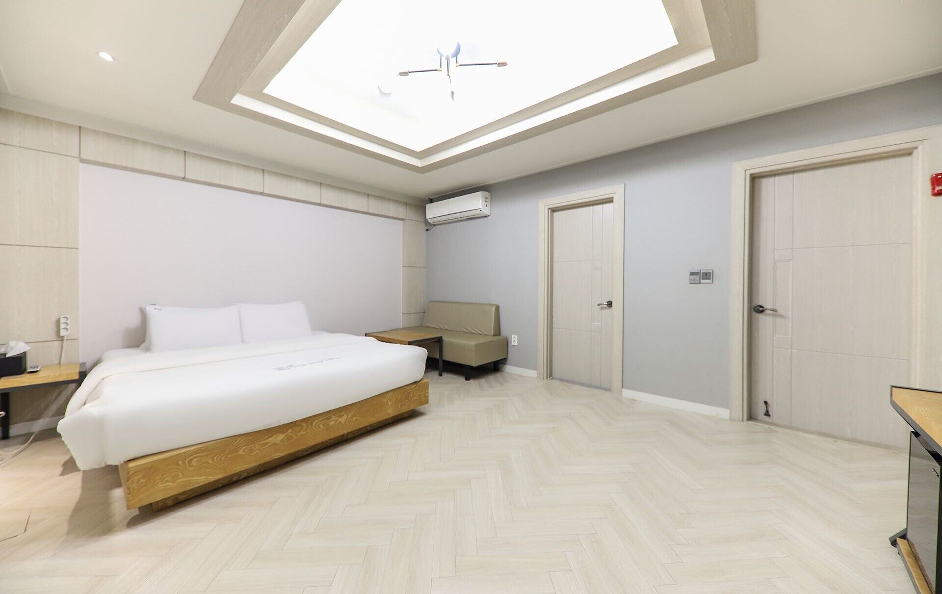 Una habitació d'hotel moderna amb un fanal, un llit, un sofà i un escriptori.