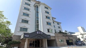 Un hotel de varios pisos con un llamativo letrero que dice 'Eco' en la entrada, indicando una iniciativa ecológica.