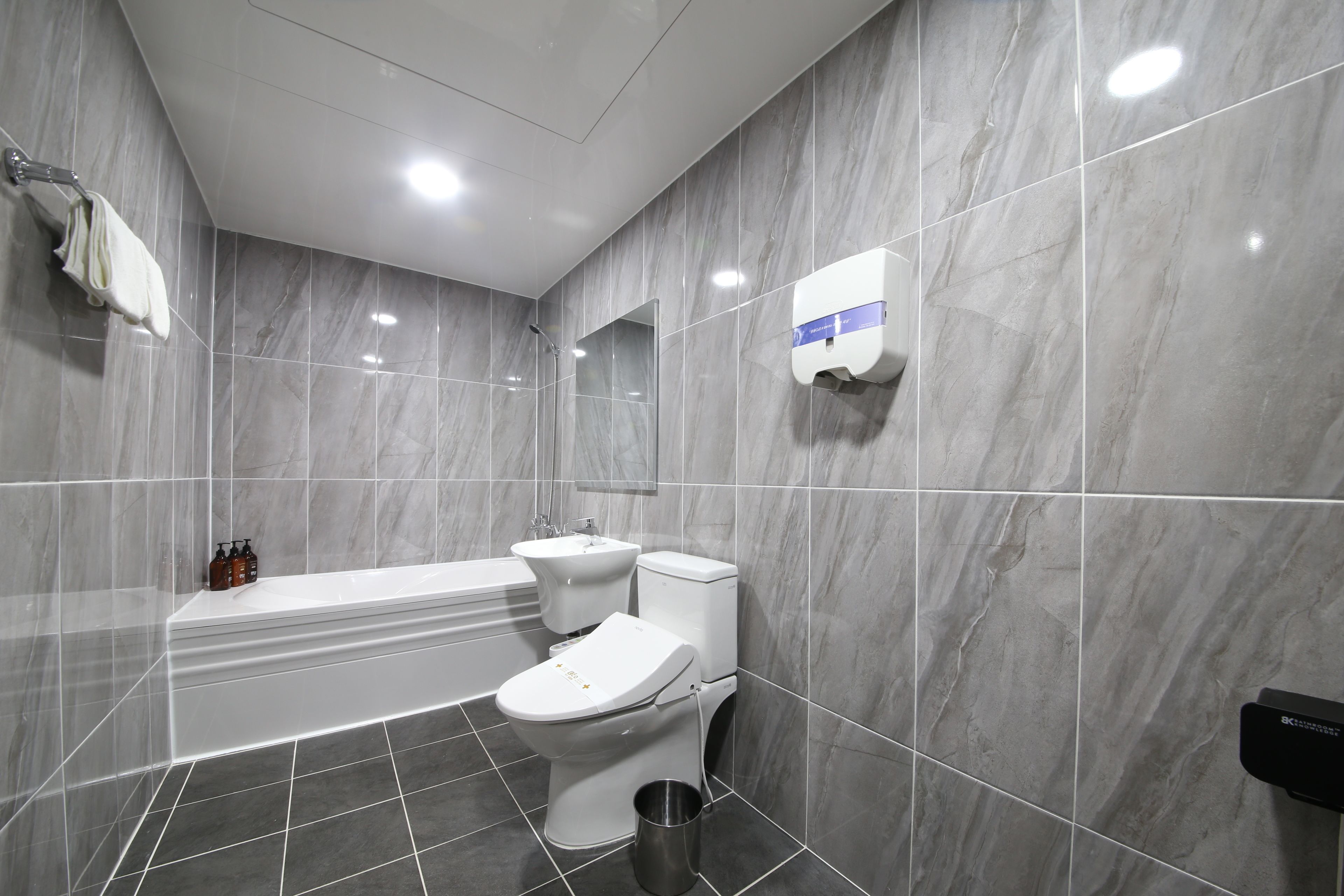 A modern bathroom with a bathtub, toilet, and sink, all in white.