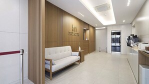 Un vestíbulo moderno de hotel con un sofá, mostrador de recepción y una estación de café.