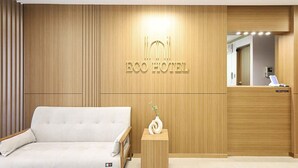 A hotel reception area with a reception desk, a sofa, and a wall-mounted sign reading "ECO HOTEL". - Eco Hotel (Mokpo)