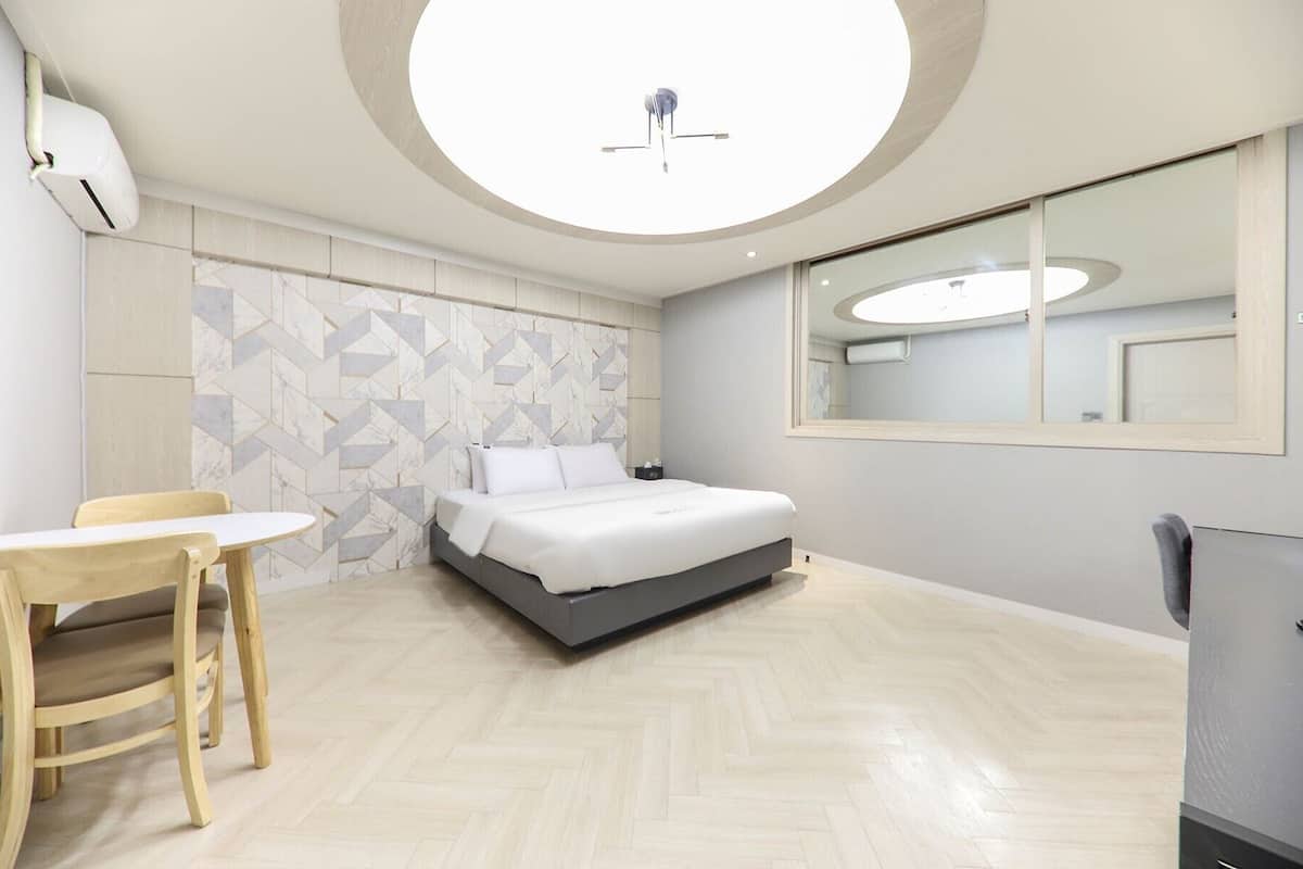 A modern hotel room with a bed, a desk, and a chair.