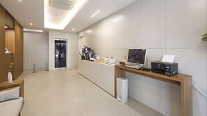 A modern reception area with a wooden desk, a printer, and a computer monitor. - Eco Hotel (Mokpo)
