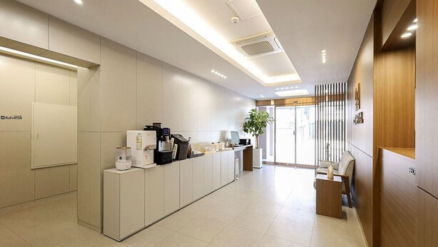 Una moderna zona de recepción con estación de café, una computadora y un área de descanso.