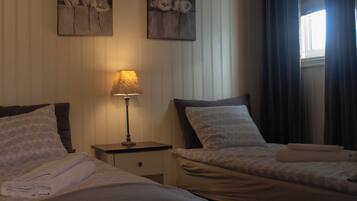A hotel room with two beds, a nightstand with a lamp, and artwork on the wall.