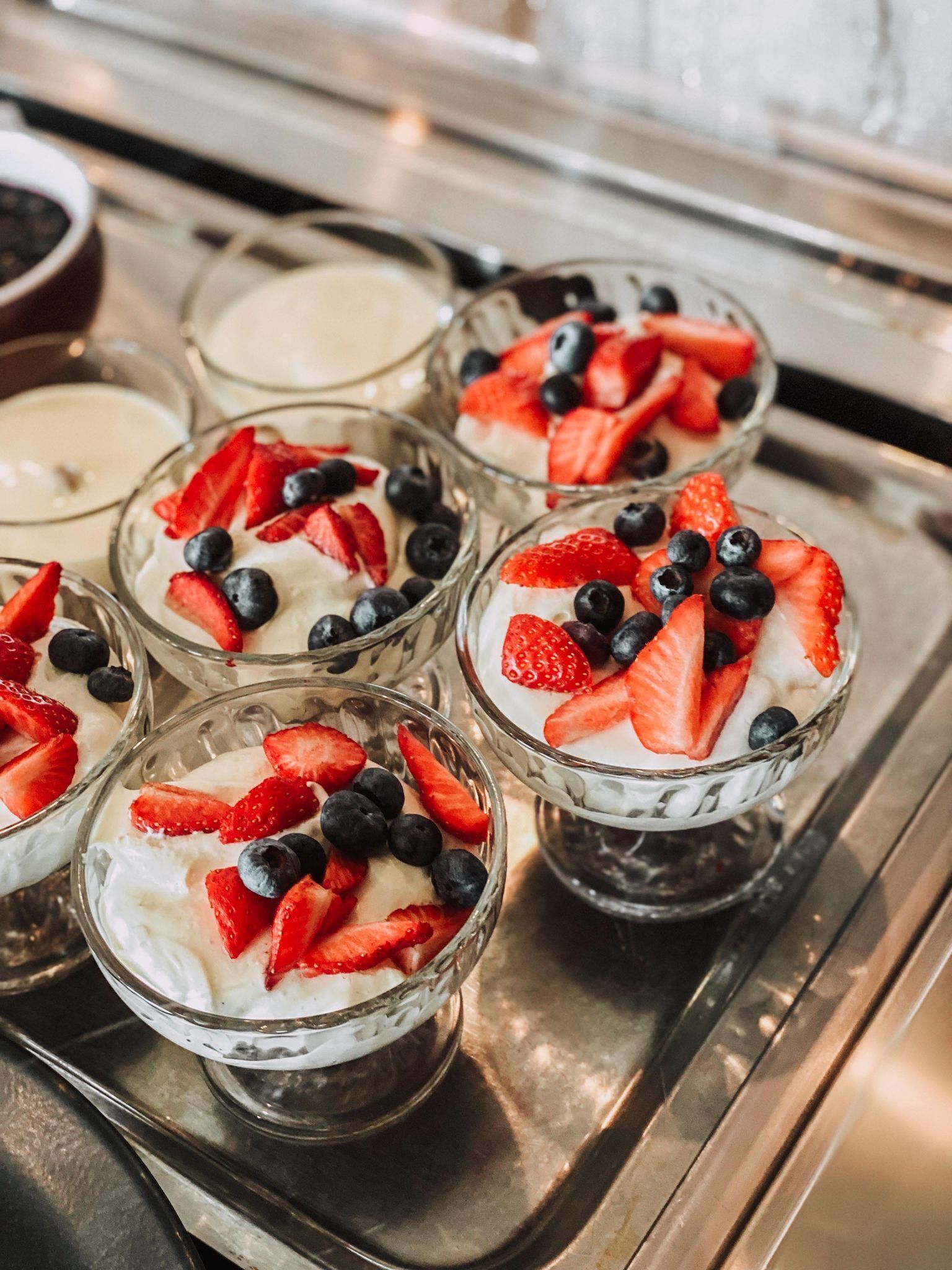 A tray of parfaits with strawberries and blueberries.