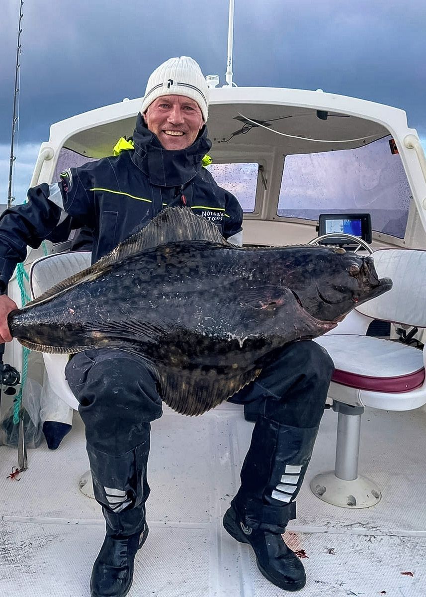 A person holding a large fish on a boat.