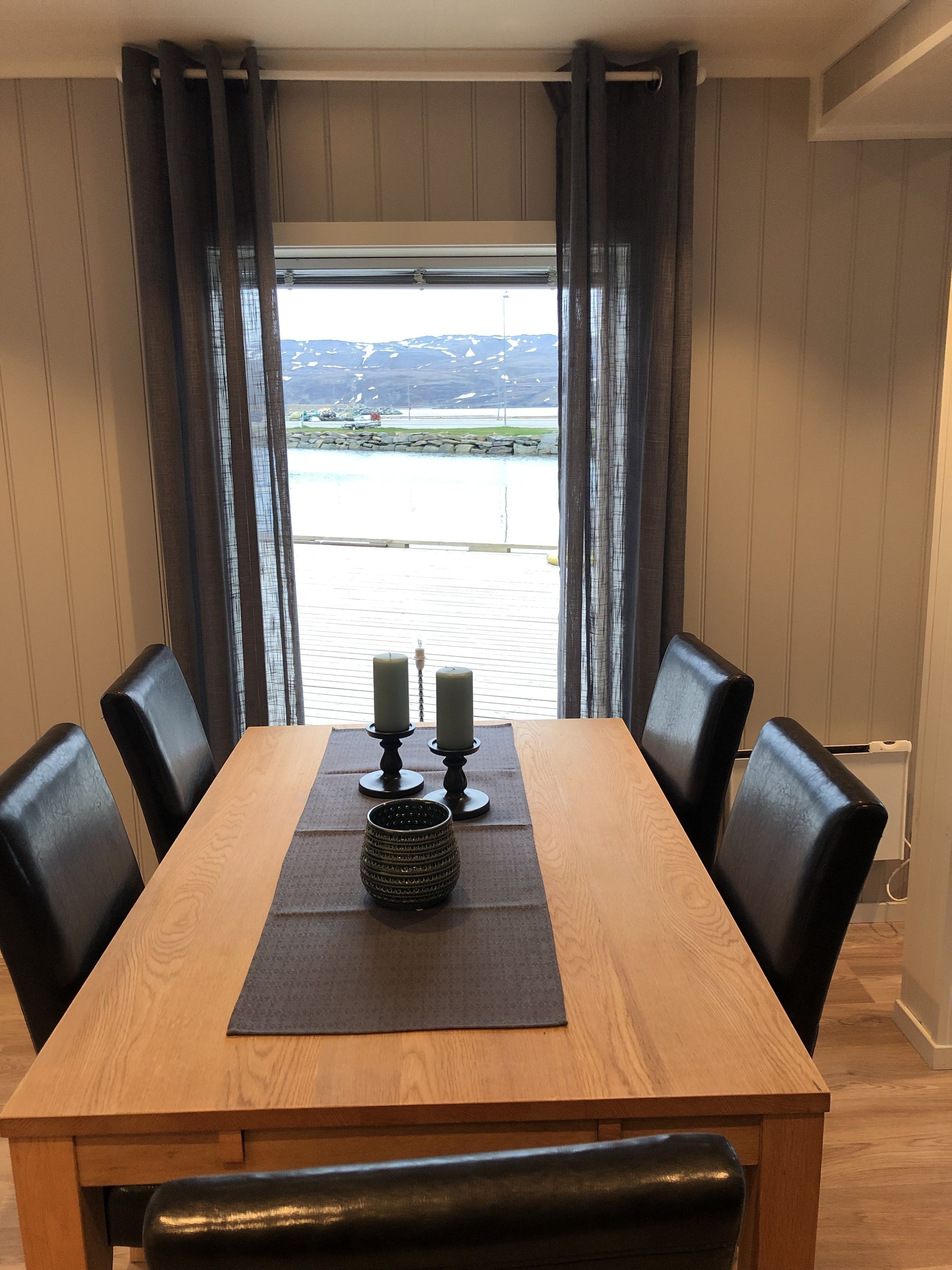 Una mesa de comedor con sillas negras, un candelabro y un mantel individual.