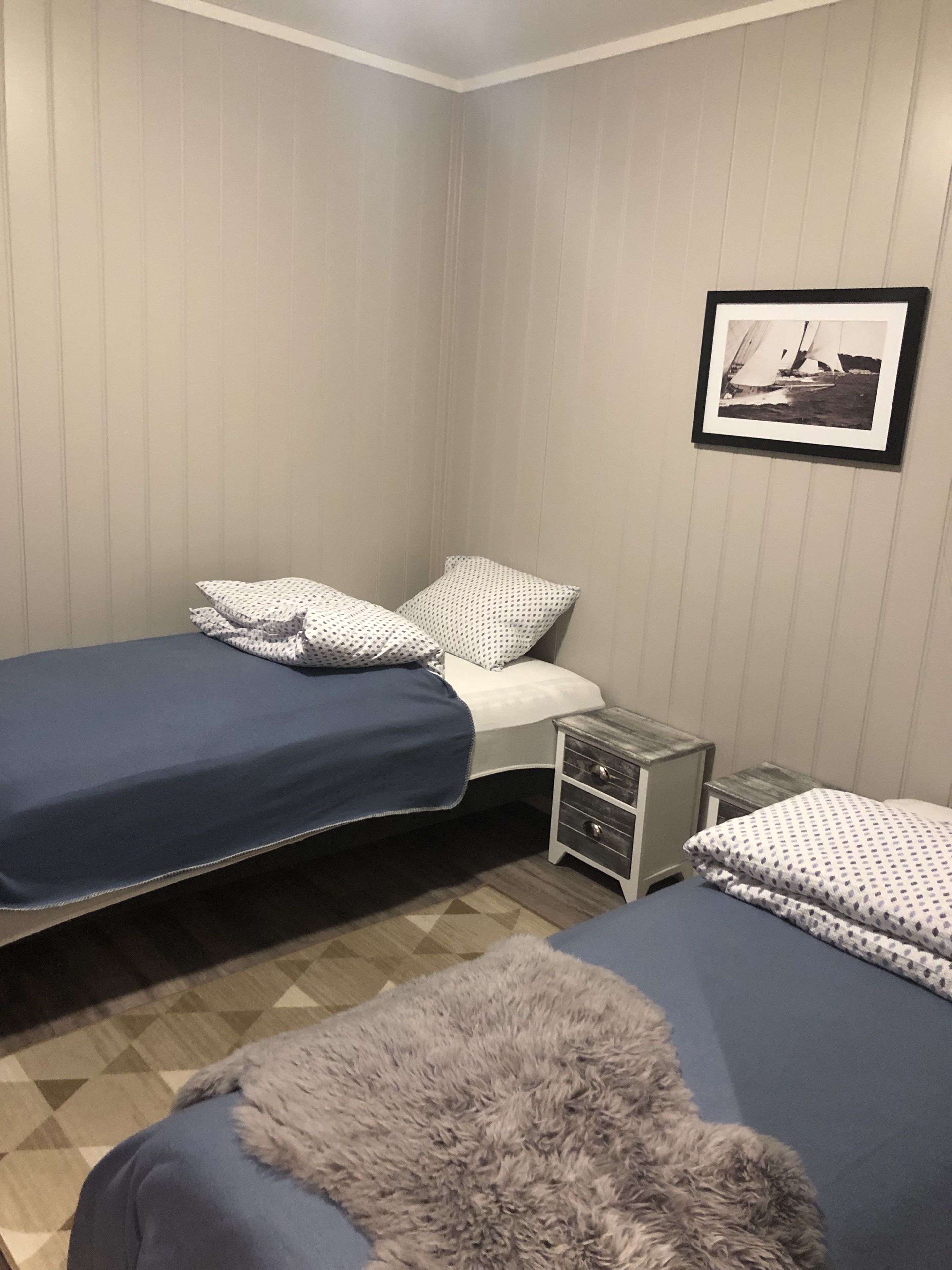 Un dormitorio con dos camas individuales, una mesita de noche, un aparador y un cuadro en la pared.