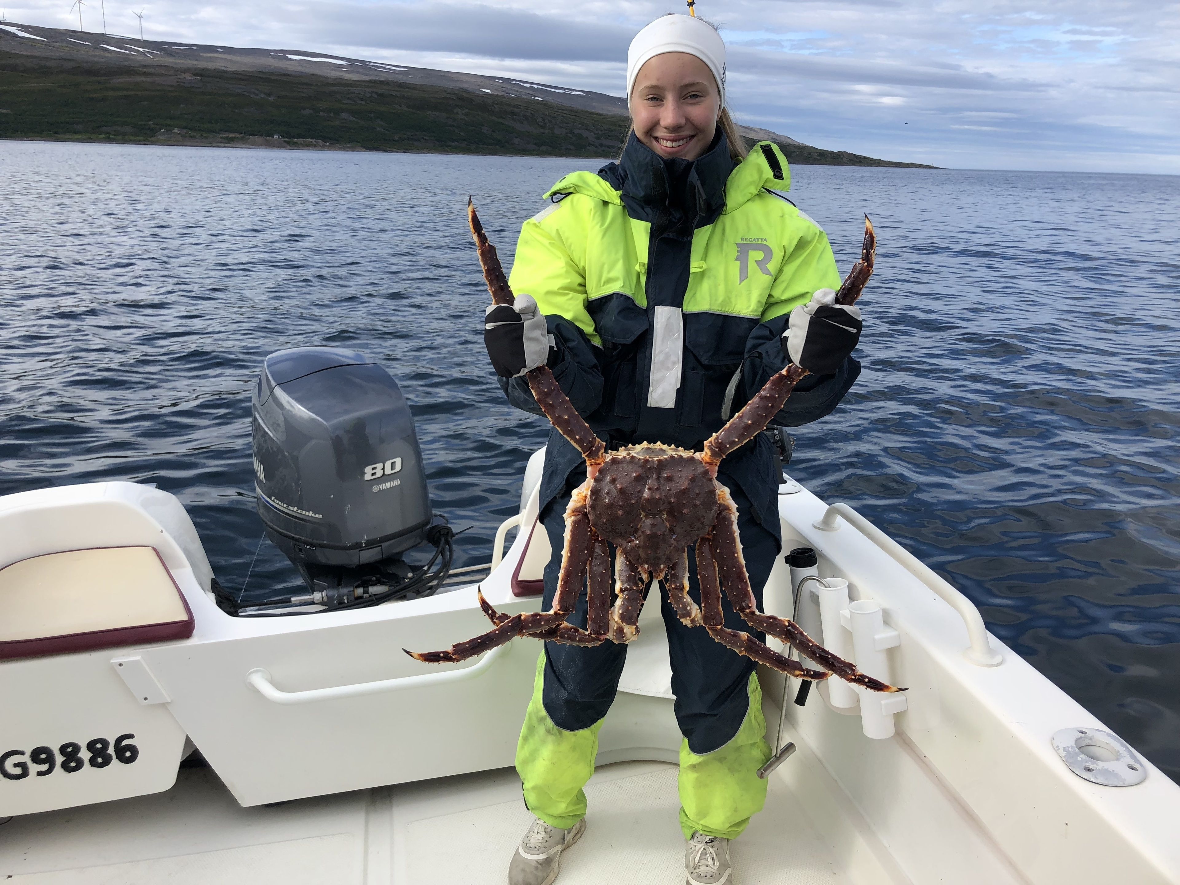 Une personne tenant un gros crabe sur un bateau équipé d'un moteur hors-bord Yamaha.