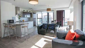Eine moderne Wohnung mit Küche, Essbereich und Wohnzimmer. Sie verfügt über ein großes Fenster, eine Couch und einen Couchtisch.