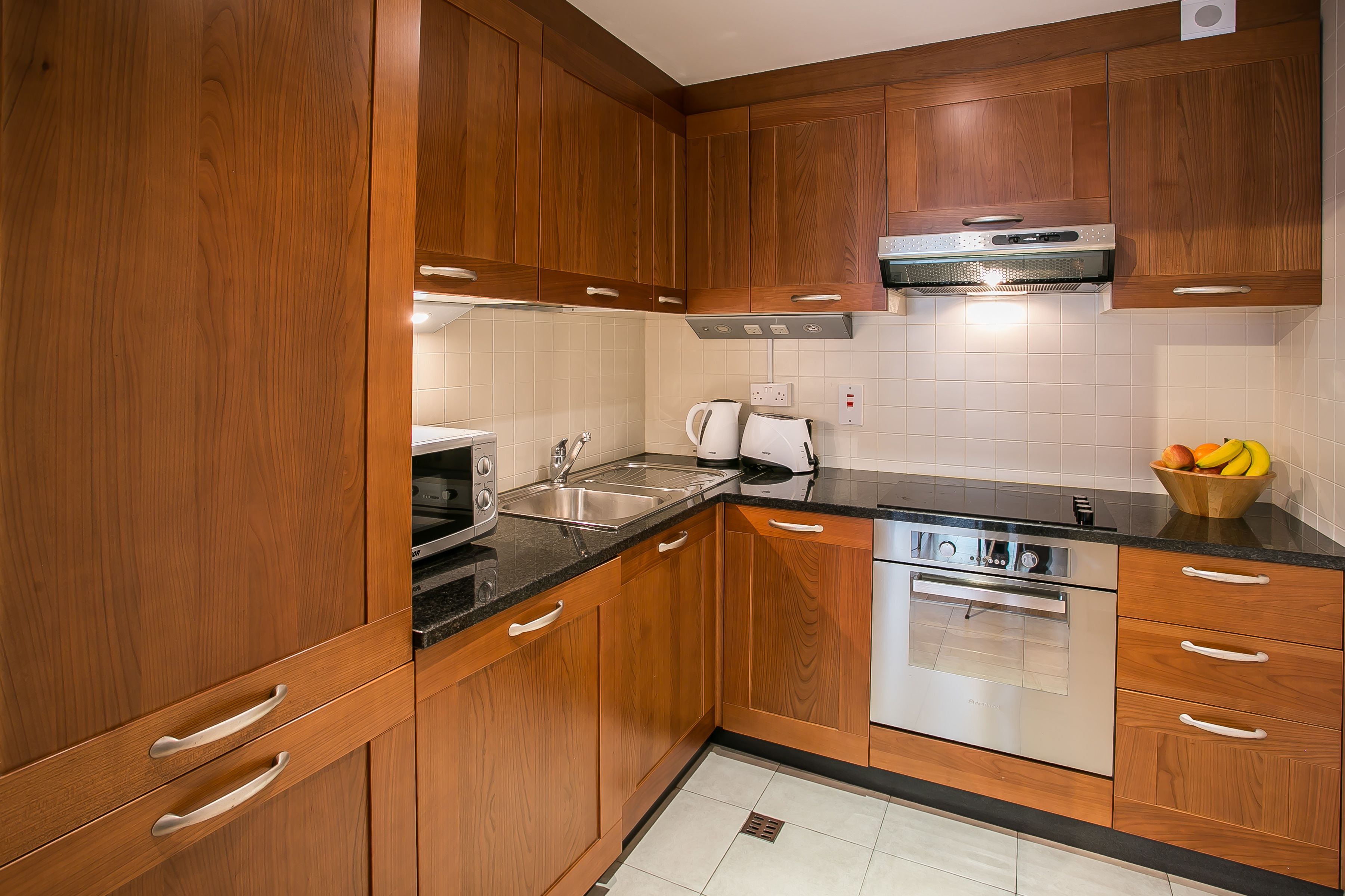Una cocina moderna con armarios de madera, electrodomésticos de acero inoxidable y encimera negra.