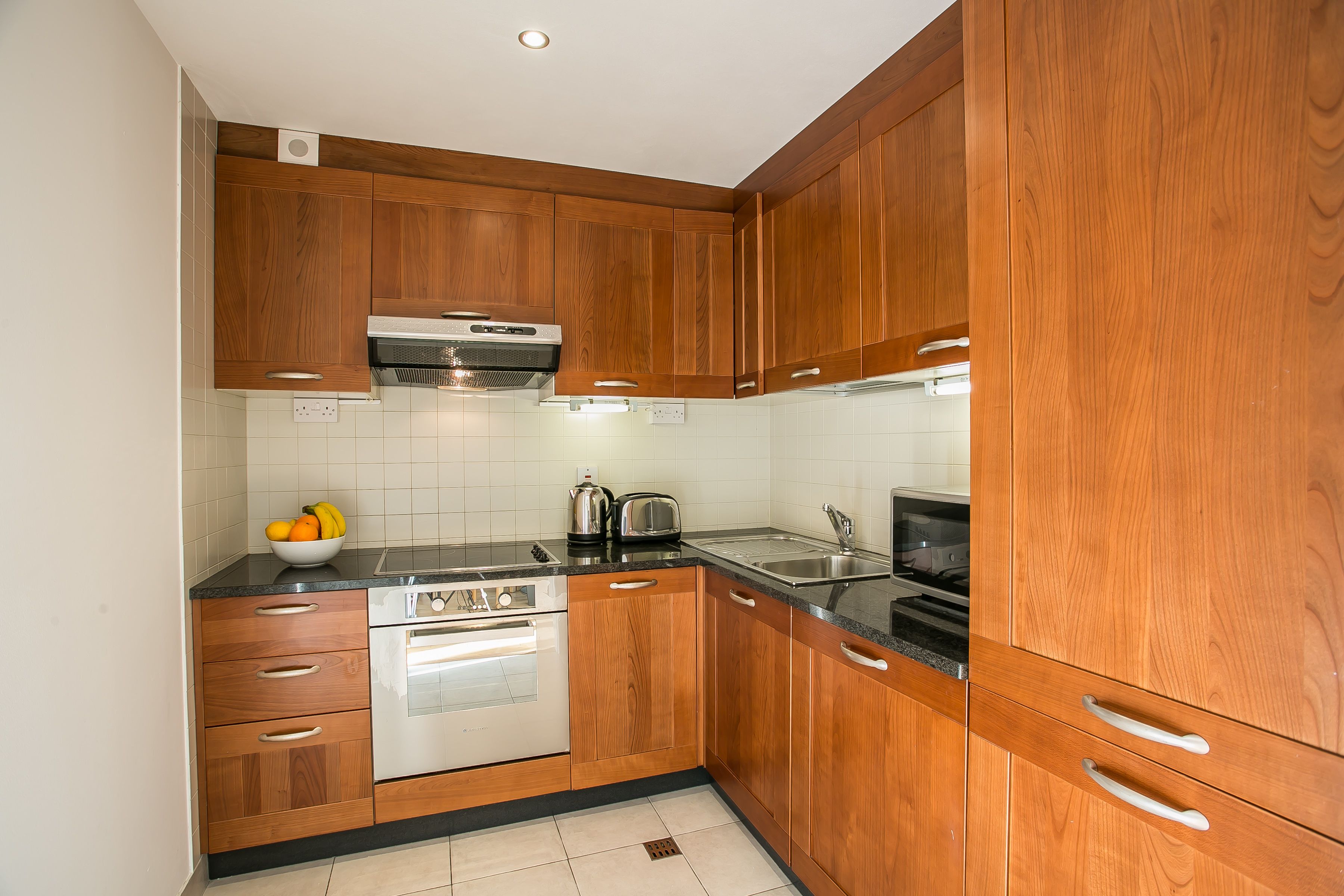 Una cocina con armarios de madera, horno de acero inoxidable y encimera negra.