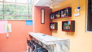 A bar area with a marble countertop, black bar stools, and shelves of liquor bottles.