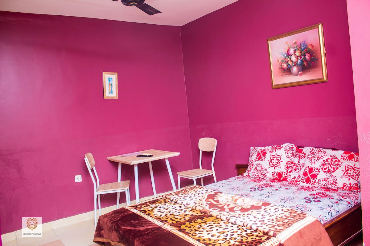 A room with a bed, a desk, and two chairs.