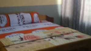 A bedroom with a bed, a painting on the wall, and curtains on the window.