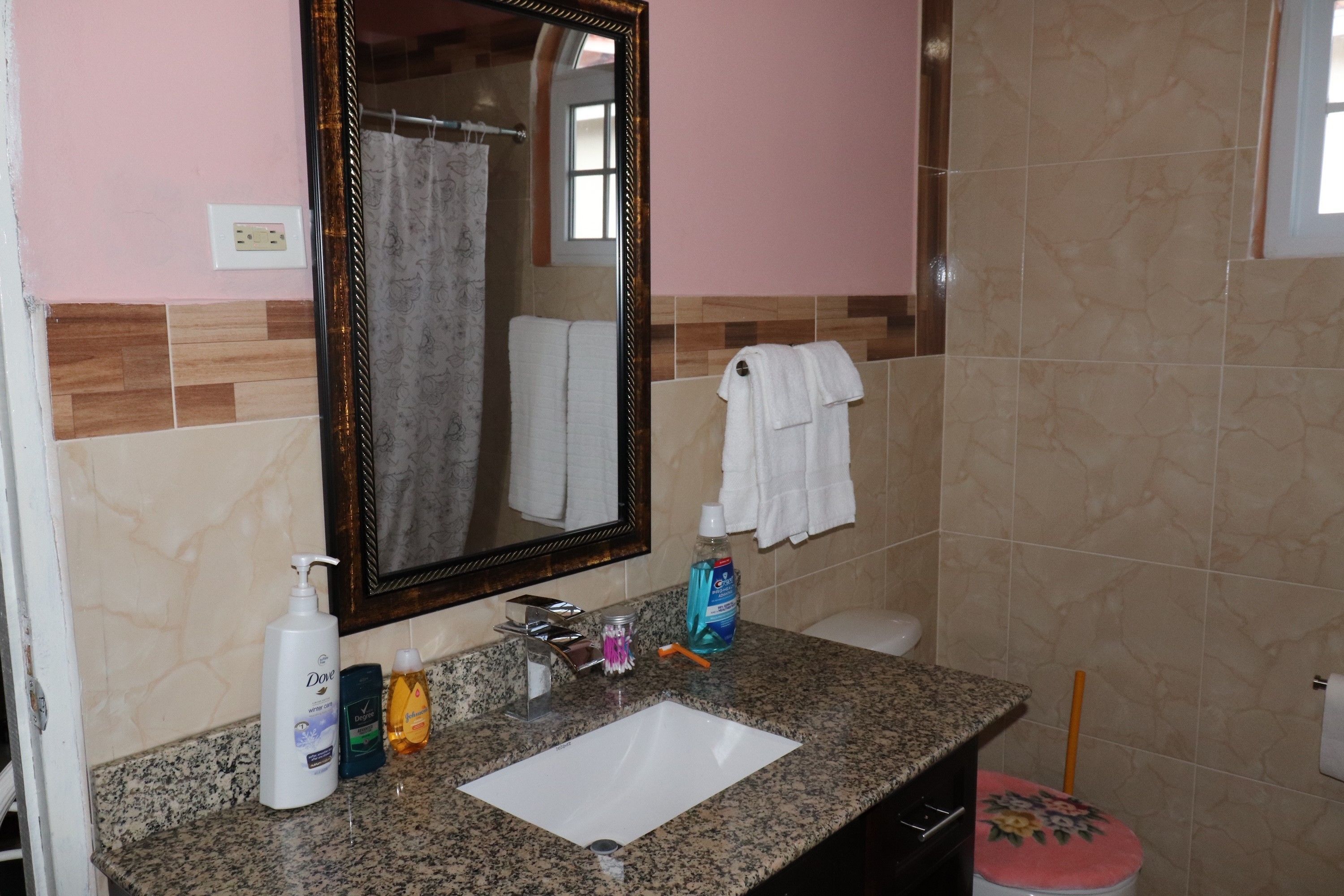 A bathroom with a sink, mirror, and toiletries.