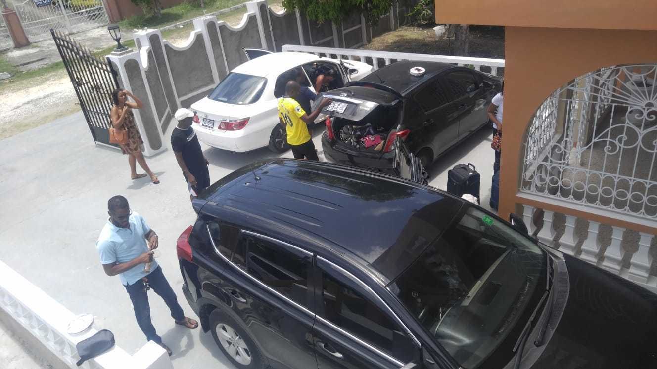 Une allée bordée de portails, avec un SUV noir garé au premier plan, une voiture blanche et une personne vêtue d’un t-shirt jaune près de la voiture blanche.