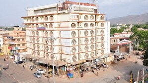 A multi-story building with a commercial ground floor and a large sign reading "SHANBHAG INTERNATIONAL". - Iroomz Shanbhag Towers International (Hospet)