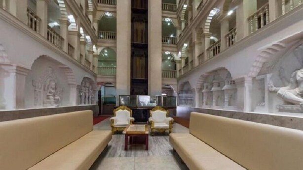 A spacious lobby with high ceilings, ornate wall carvings, and a central seating area with sofas and armchairs. - Iroomz Shanbhag Towers International (Hospet)