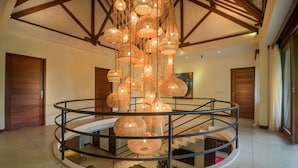 A spacious interior with a central circular staircase surrounded by a railing, a high ceiling with exposed wooden beams, and multiple hanging wicker lamps. - Large Groups,9 BDR,Close To Beach,Great Inclusions (Canggu)