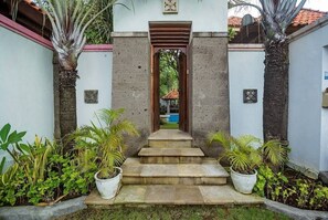 Steps lead to a welcoming entrance, flanked by lush greenery and decorative plants.