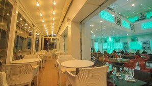 A restaurant with multiple tables and chairs, a glass partition, and a ceiling with recessed lighting. - Hotel Kenzo (Safi)