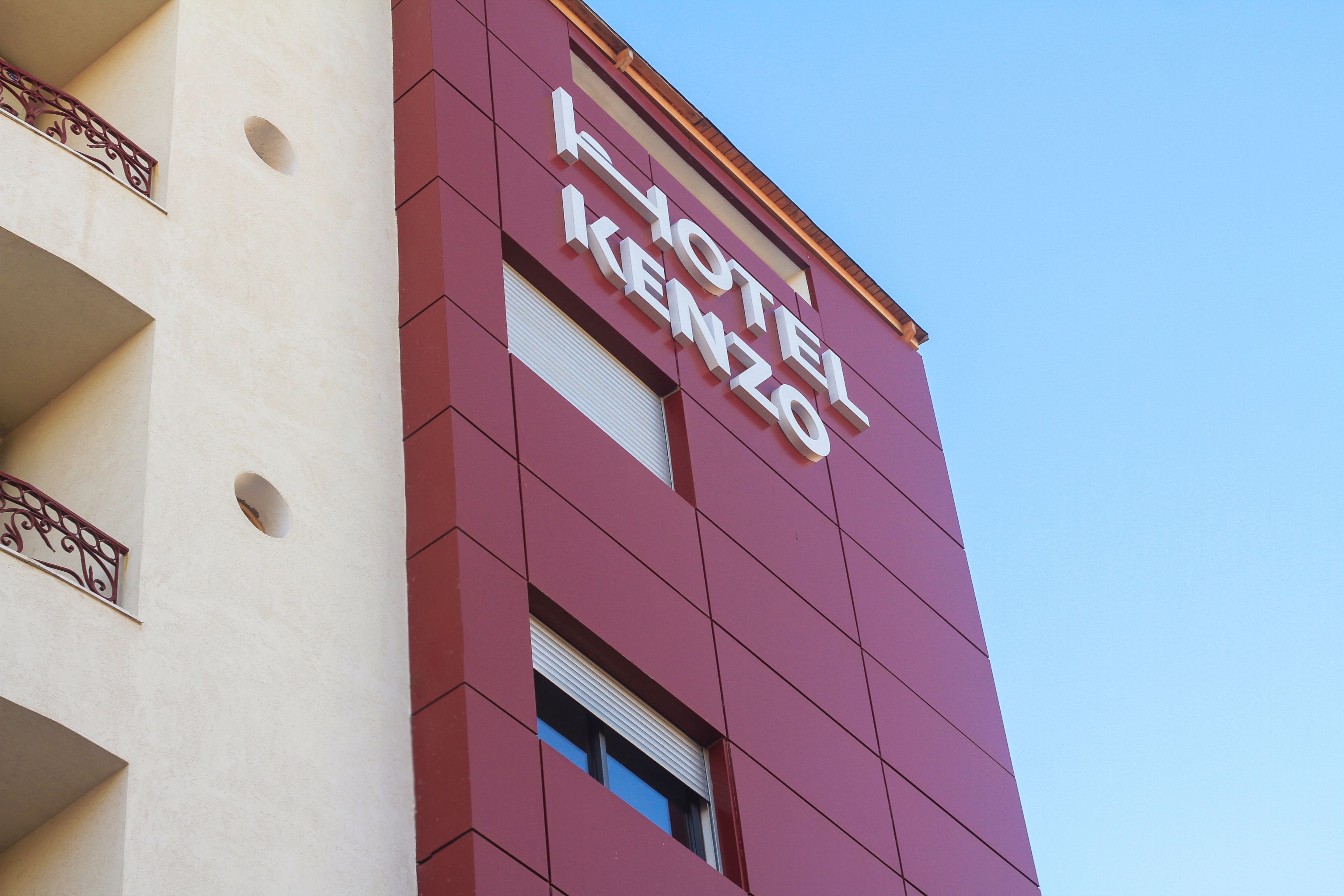 A hotel sign with the name "HOTEL KENZO" on a red building facade.
