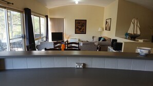 Ein modernes Wohnzimmer mit Flachbildfernseher, einer Couch, einem Couchtisch und einem Essbereich mit Stühlen.