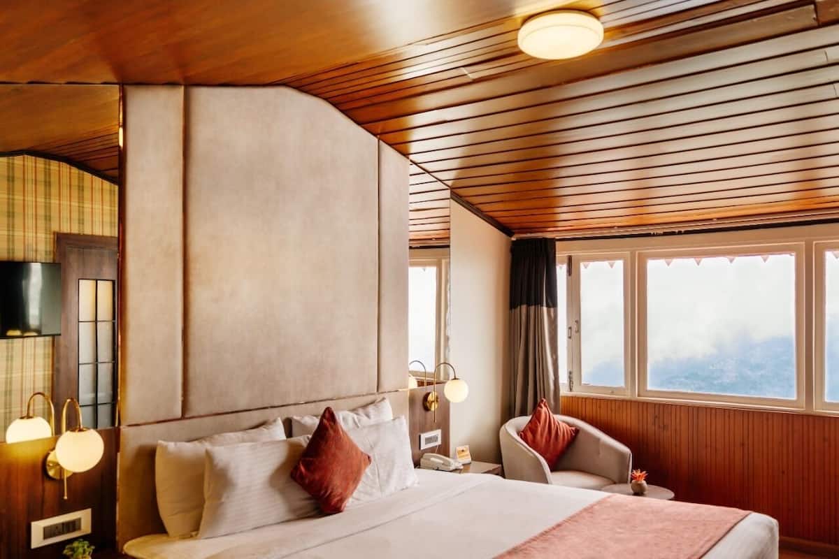 Een hotelkamer met een groot bed, een stoel, een nachtkastje en een raam met uitzicht.