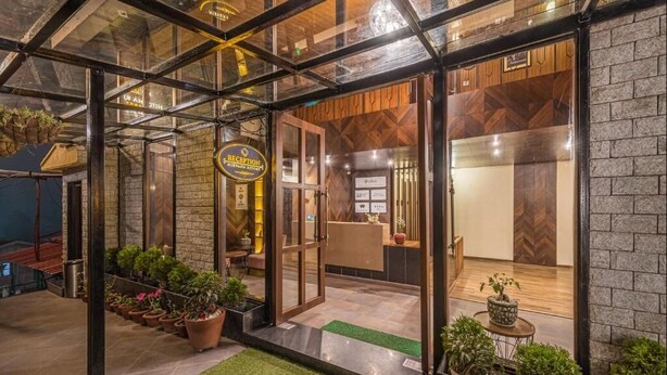 Uma área de recepção com balcão de madeira, portas de vidro e plantas em vasos.