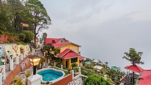 Hotel numa encosta com piscina, edifícios de telhado vermelho e escadaria que dá acesso à propriedade.