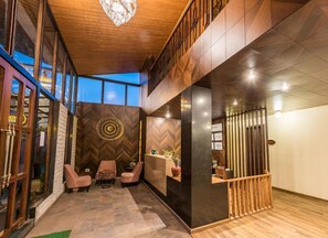 A modern reception area with a wooden ceiling, a herringbone-patterned wall, and a reception desk. - Udaan Nirvana Resort Darjeeling (Darjeeling)