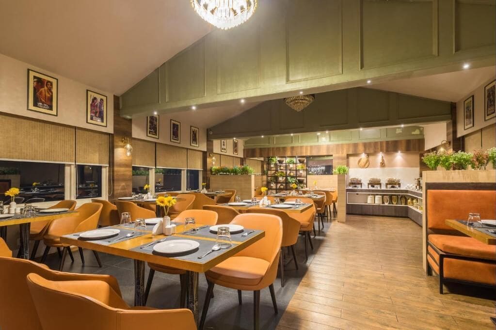 Un restaurante con sillas color naranja, mesas de madera y un candelabro.