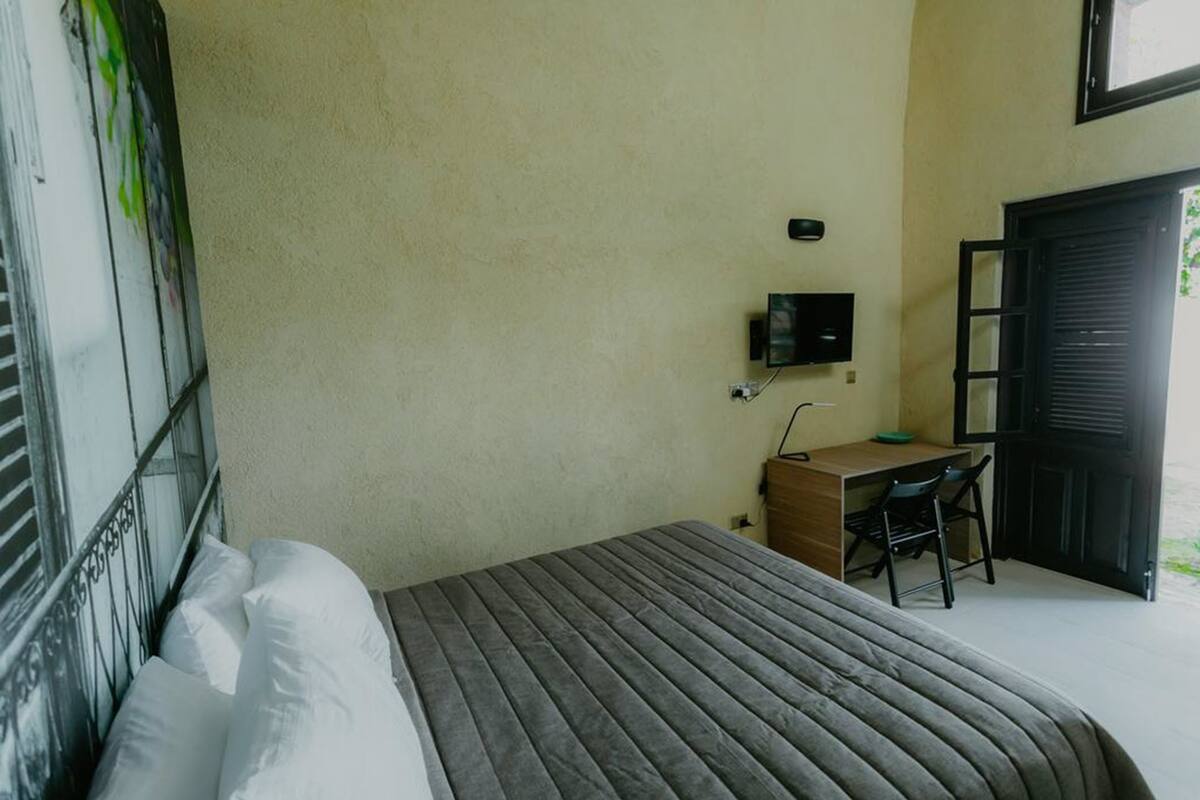 A bedroom with a bed, a desk, and a chair.